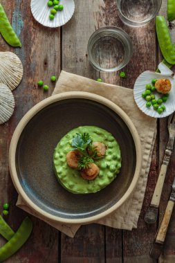 Bir tabakta bezelye püresi ile Kavrulmuş Tarak
