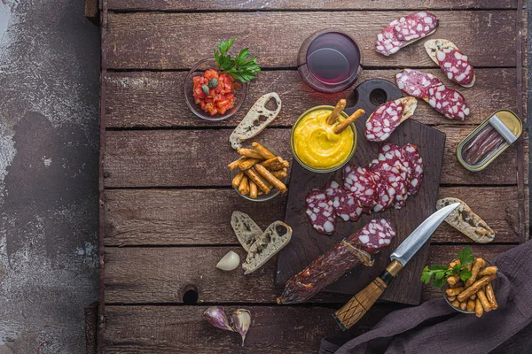 Kırmızı şarap ve charcuterie kurulu: salam, kabuklu ekmek, chochoves, kopya alanı