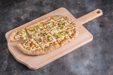 Tahta tahtada servis edilen tavuk ve turşulu lezzetli pizza.