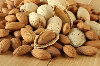 Soyulmuş ham badem ve ahşap masa üzerinde kabukları ile çiğ badem yığını. Portre