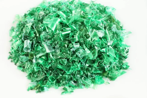 Küçük parçalar halinde kesilmiş yeşil plastik şişe beyaz kağıt üzerinde