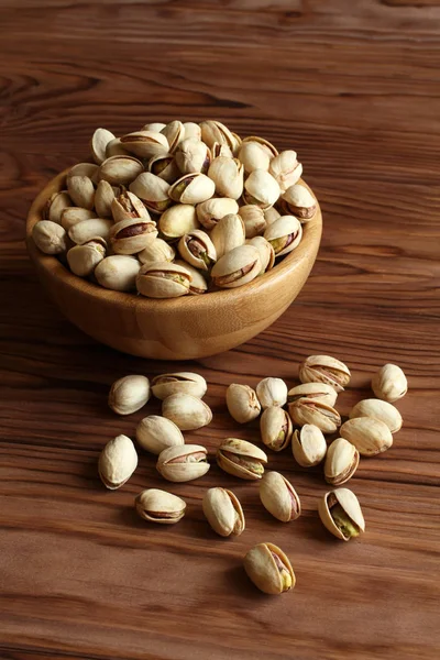 Salted dried pistachio nuts in bamboo bowl on wooden background — Stock Photo, Image
