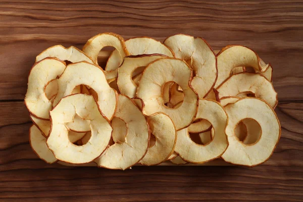 Apple chips lying on a bamboo plate on a wooden table. Closeup.