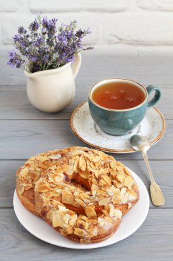 Badem ezmesi serpiştirilmiş krakerler ve gri ahşap bir masada bir fincan bitki çayı. Yakın çekim.