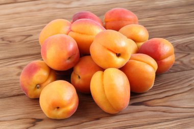 Kahverengi ahşap bir masada olgun kayısılar. Gün ışığı. Yakın çekim.     