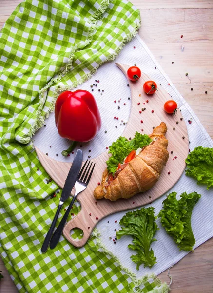 Vista superior del desayuno casero fácil con cruasanes frescos, jamón, pimiento rojo y queso en el sándwich, jugo de tomate y taza de café caliente con leche en una mesa de madera . — Foto de Stock