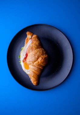 Mavi arka planı olan siyah bir tabakta kruvasan.