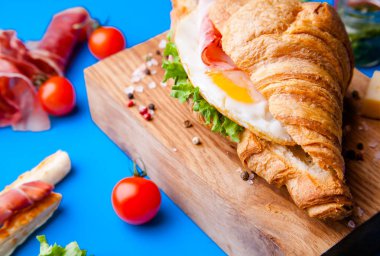 Jambonlu, peynirli, kekikli ve incirli taze kruvasan sandviçi.