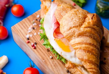 Jambonlu, peynirli, kekikli ve incirli taze kruvasan sandviçi.