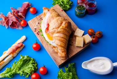 Jambonlu, peynirli, kekikli ve incirli taze kruvasan sandviçi.