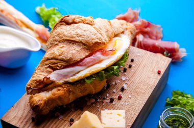 Jambonlu, peynirli, kekikli ve incirli taze kruvasan sandviçi.