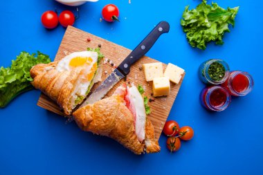 Jambonlu, peynirli, kekikli ve incirli taze kruvasan sandviçi.