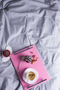 Pasta ve kakao ile yatakta lezzetli ve lezzetli bir kahvaltı. Turuncu sonbahar meyvelerinin yanında, ahşap tahtanın üzerinde pembe fincanda taze fırın ve kahve. Sonbahar sabahı kavramı.