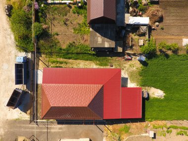 Bir gölgelik avlu üzerinde olan bir ev. Oluklu metal profil çatıdan. Metal kiremit