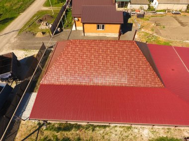 Bir gölgelik avlu üzerinde olan bir ev. Oluklu metal profil çatıdan. Metal kiremit