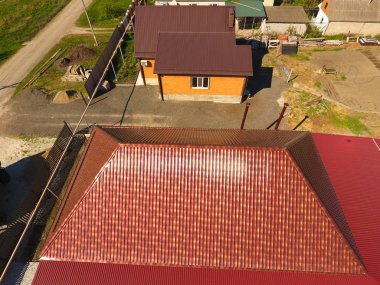 Bir gölgelik avlu üzerinde olan bir ev. Oluklu metal profil çatıdan. Metal kiremit