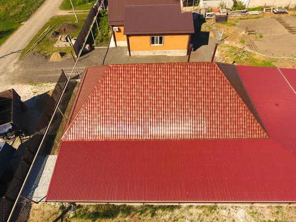 Bir gölgelik avlu üzerinde olan bir ev. Oluklu metal profil çatıdan. Metal kiremit