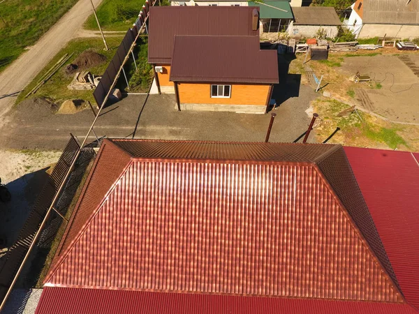 Bir gölgelik avlu üzerinde olan bir ev. Oluklu metal profil çatıdan. Metal kiremit