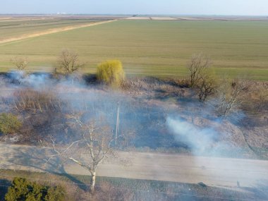 Sulama kanalı kuru ot yakma. Duman ve kuru ot alevi. Yanmış kuru ot