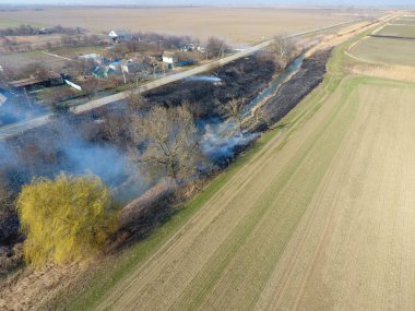 Sulama kanalı kuru ot yakma. Duman ve kuru ot alevi. Yanmış kuru ot