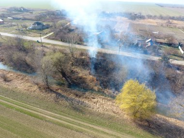 Sulama kanalı kuru ot yakma. Duman ve kuru ot alevi. Yanmış kuru ot