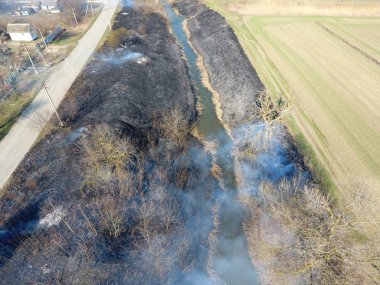 Sulama kanalı kuru ot yakma. Duman ve kuru ot alevi. Yanmış kuru ot