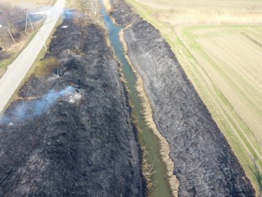 Sulama kanalı kuru ot yakma. Duman ve kuru ot alevi. Yanmış kuru ot