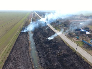 Sulama kanalı kuru ot yakma. Duman ve kuru ot alevi. Yanmış kuru ot