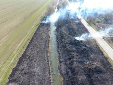 Sulama kanalı kuru ot yakma. Duman ve kuru ot alevi. Yanmış kuru ot