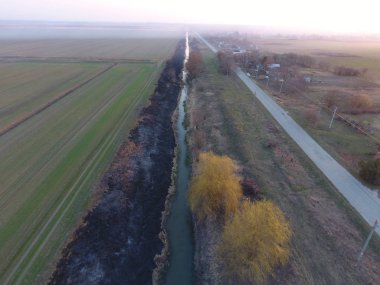 Yanık sazlık ve kıyı ile sulama kanalı. Çim küllerinden