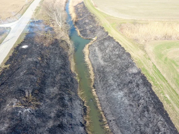 Sulama kanalı kuru ot yakma. Duman ve kuru ot alevi. Yanmış kuru ot