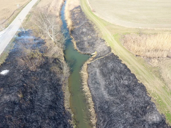 Sulama kanalı kuru ot yakma. Duman ve kuru ot alevi. Yanmış kuru ot