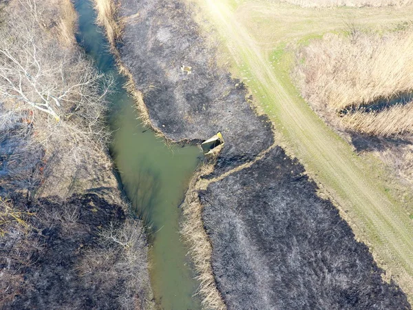 Sulama kanalı kuru ot yakma. Duman ve kuru ot alevi. Yanmış kuru ot