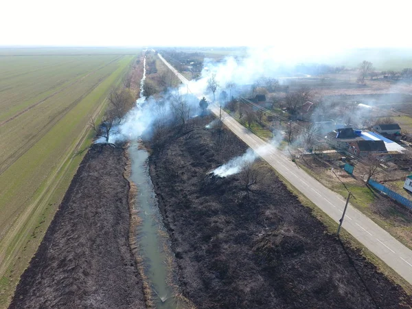 Sulama kanalı kuru ot yakma. Duman ve kuru ot alevi. Yanmış kuru ot