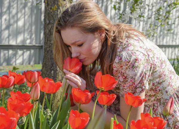 Rapariga a cheirar tulipas. A menina entre as flores . — Fotografia de Stock