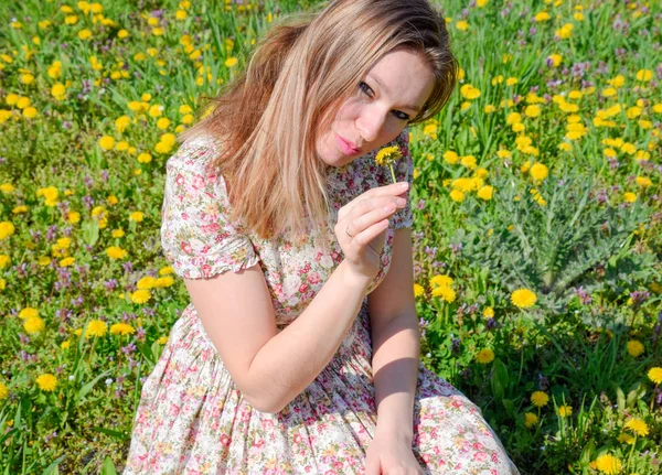 Uma menina em um vestido em uma clareira com dentes de leão. A menina entre as flores — Fotografia de Stock