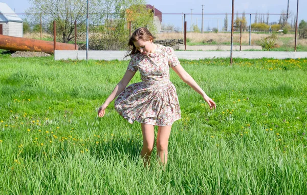 Uma rapariga de vestido numa clareira. A menina está entre a grama . — Fotografia de Stock