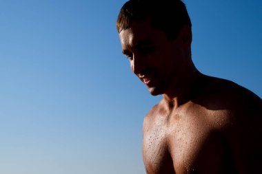 Bir mavi gökyüzü ve güneş karşı bir insan silüeti. Bir erkekte deniz su damlaları