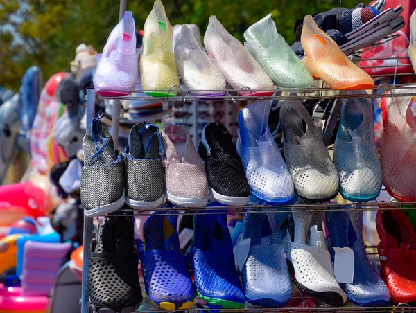 Rubber and silicone sandals and sneakers on the shoe shelf in the market.