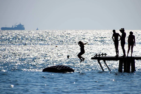 Силуэты Людей Прыгающих Морского Причала Отдых Морском Пляже — стоковое фото