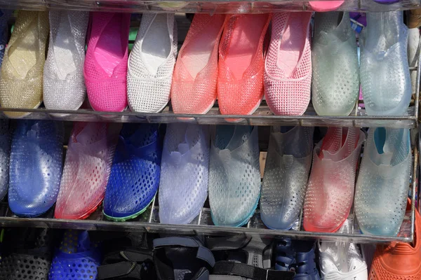 Sandali e scarpe da ginnastica in gomma e silicone sullo scaffale delle scarpe sul mercato — Foto Stock