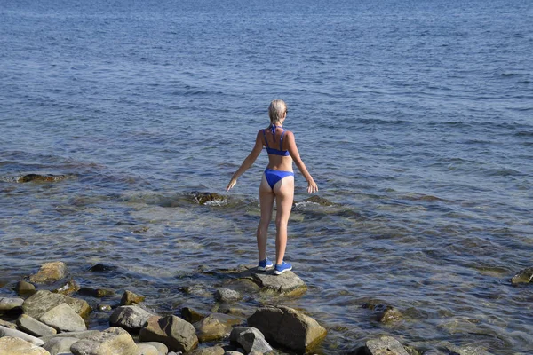 Ein schönes Mädchen im blauen Bikini geht die Seebrücke zum Meer entlang. Schiffsbeton-Pier. Sprung von der Seebrücke ins Wasser. schöne Beute Mädchen — Stockfoto