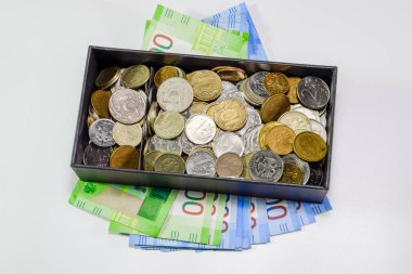Coins of different denominations in a piggy bank box. Paper rubles under the piggy bank. New banknotes of Russia clipart