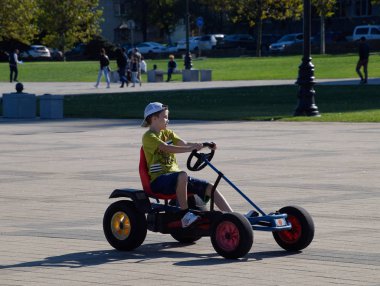 Çocuklar parkta pedallar ile arabalara binmek. Amiral Serebryakov Meydanı. Çocuk eğlence.
