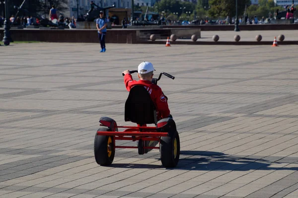 Barn rida i parken på bilar med pedaler. Amiral Serebryakov Square. Barnens fritid. — Stockfoto