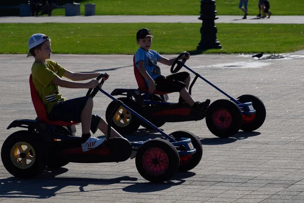 Dzieci jeżdżą w parku na samochody z pedałami. Admirał Sieriebriakow Square. Wypoczynek dla dzieci. — Zdjęcie stockowe