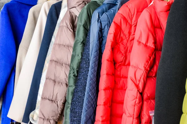 Kabáty a bundy na ramínkách v obchodě. Prodej svrchního oblečení. — Stock fotografie