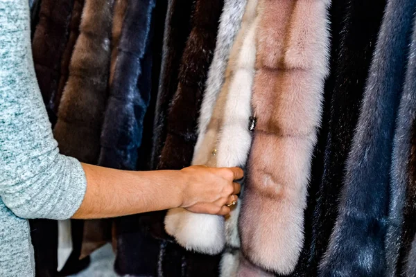 女の子は、毛皮のコートに毛皮を触れます。店で毛皮のコートを選択します。 — ストック写真