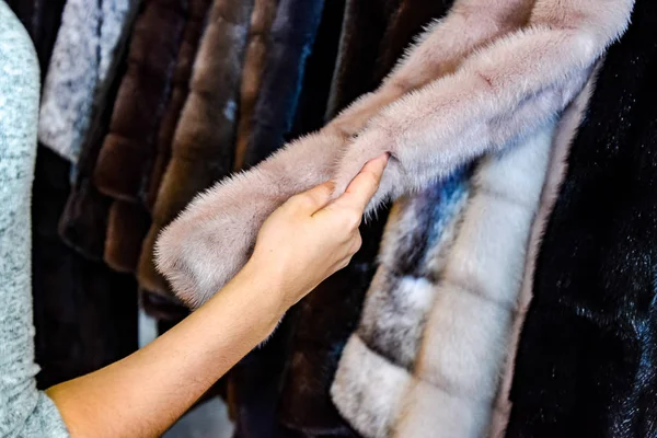 La chica toca la piel del abrigo de piel. Elegir un abrigo de piel en la tienda —  Fotos de Stock