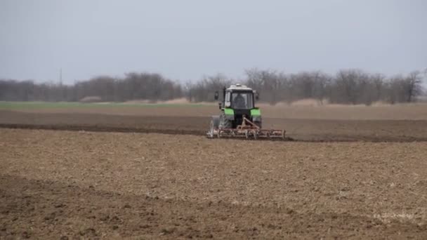 Weelderige en los van de bodem op het veld voor het zaaien. De trekker plows een veld met een ploeg. — Stockvideo